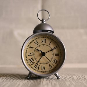 Close-up of an antique alarm clock displaying time with classic Roman numerals.